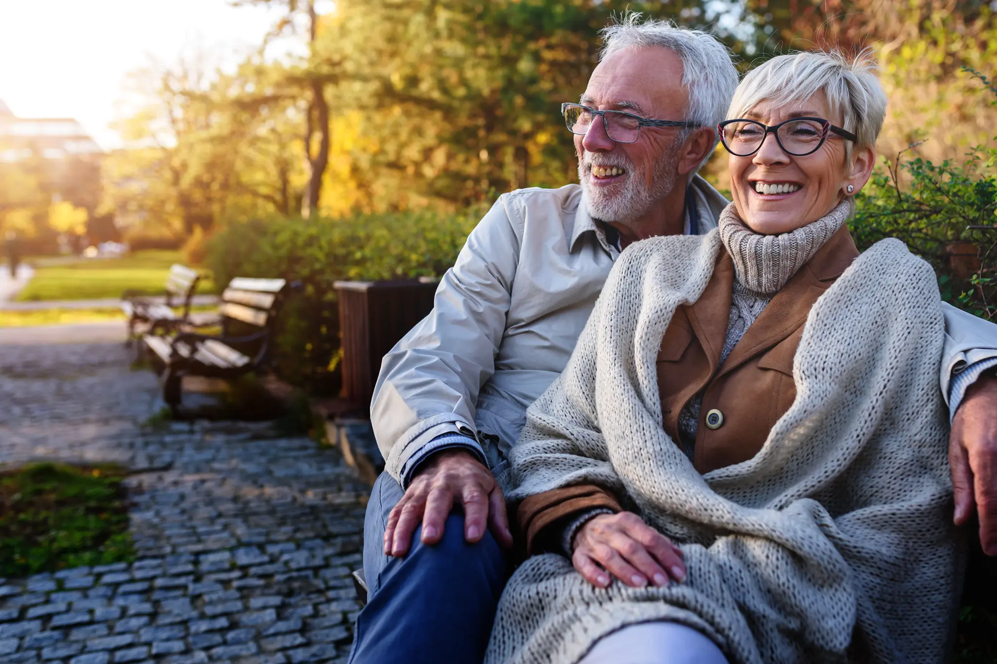 An older couple smiling on a bench.